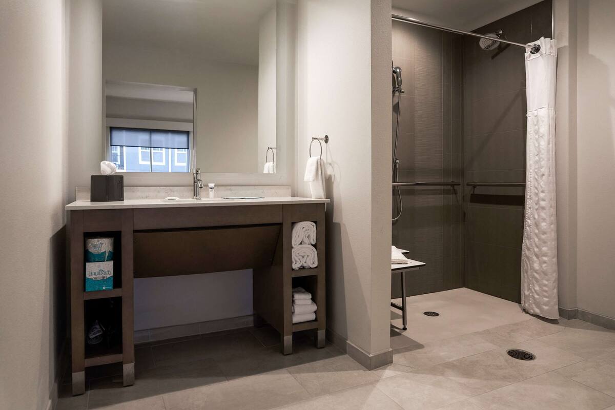 Une salle de bain moderne équipée d’une douche, d’un lavabo et d’un meuble-lavabo.