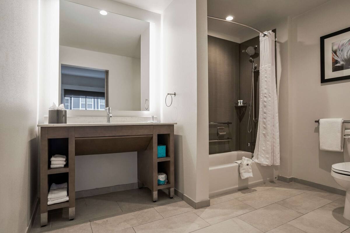 Une salle de bain moderne avec un grand miroir, une douche et des toilettes.