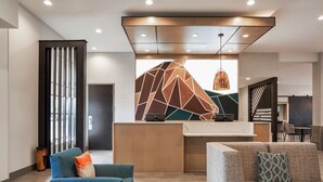 A modern lobby with a reception desk, seating area, and a geometric wall design.