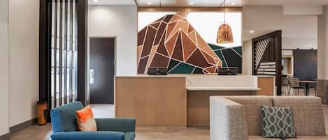 Un moderno vestíbulo con mostrador de recepción, zona de estar y un diseño de pared geométrico.