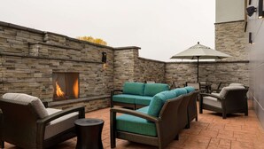 A patio area with stone walls, a fire feature, and wicker furniture.