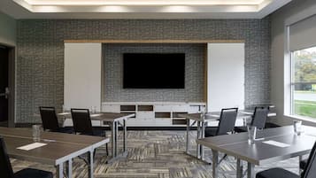 A conference room with a large flat-screen TV, whiteboard, and storage cabinets.