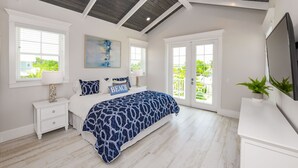 A bedroom with a bed, a nightstand, a TV, and a large window. - Putting green, Rooftop Deck AND Beach/Gulf Views with Private Heated Pool/Spa. (Lido Key)