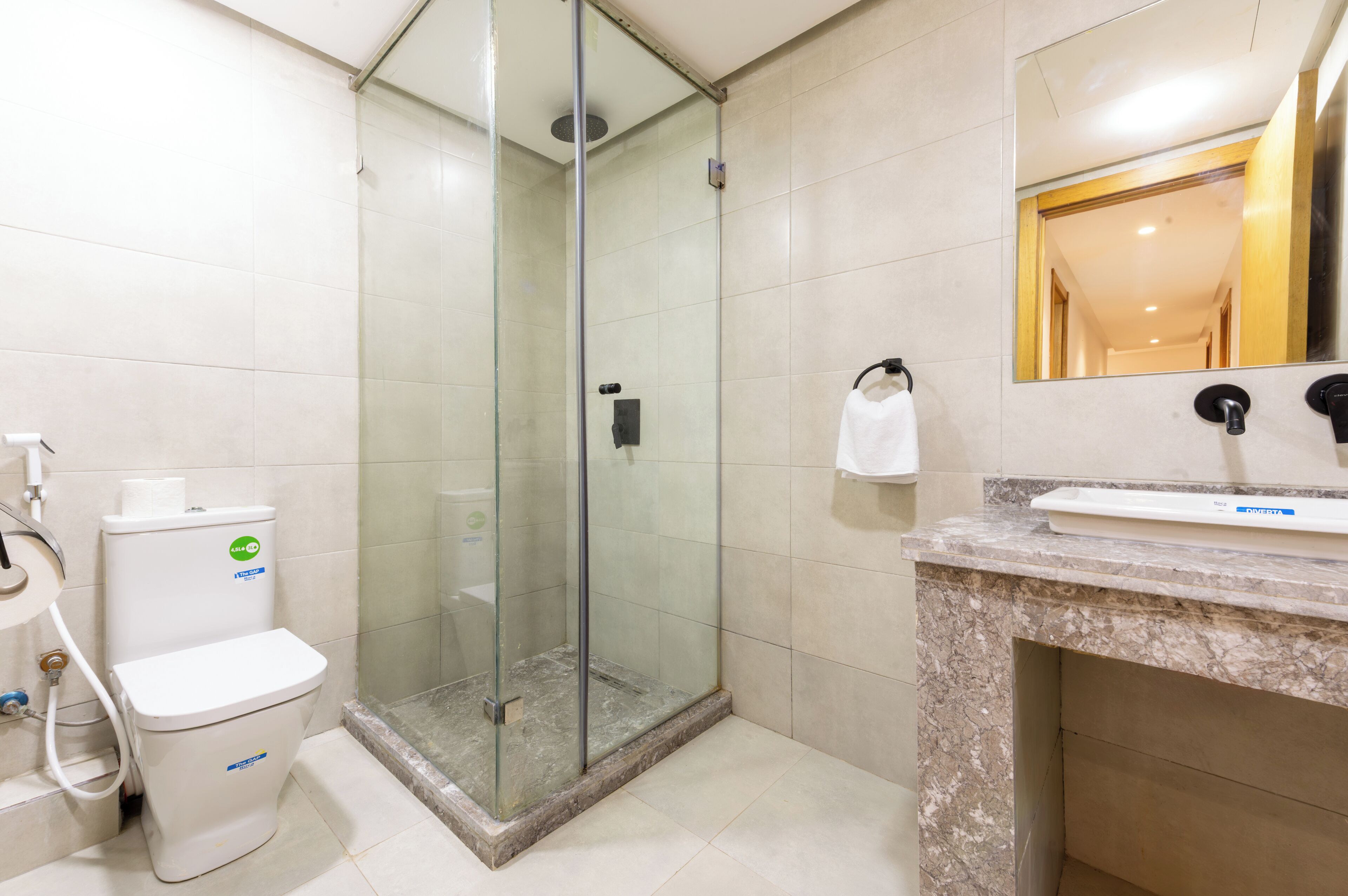 A bathroom with a glass-enclosed shower, a toilet, and a sink with a marble countertop.