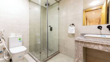 A bathroom with a glass-enclosed shower, a toilet, and a sink with a marble countertop.