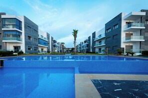 A modern hotel with a central swimming pool, multiple balconies, and contemporary architecture. - Garden Bay Appart'Hôtel (Soualem Trifiya)