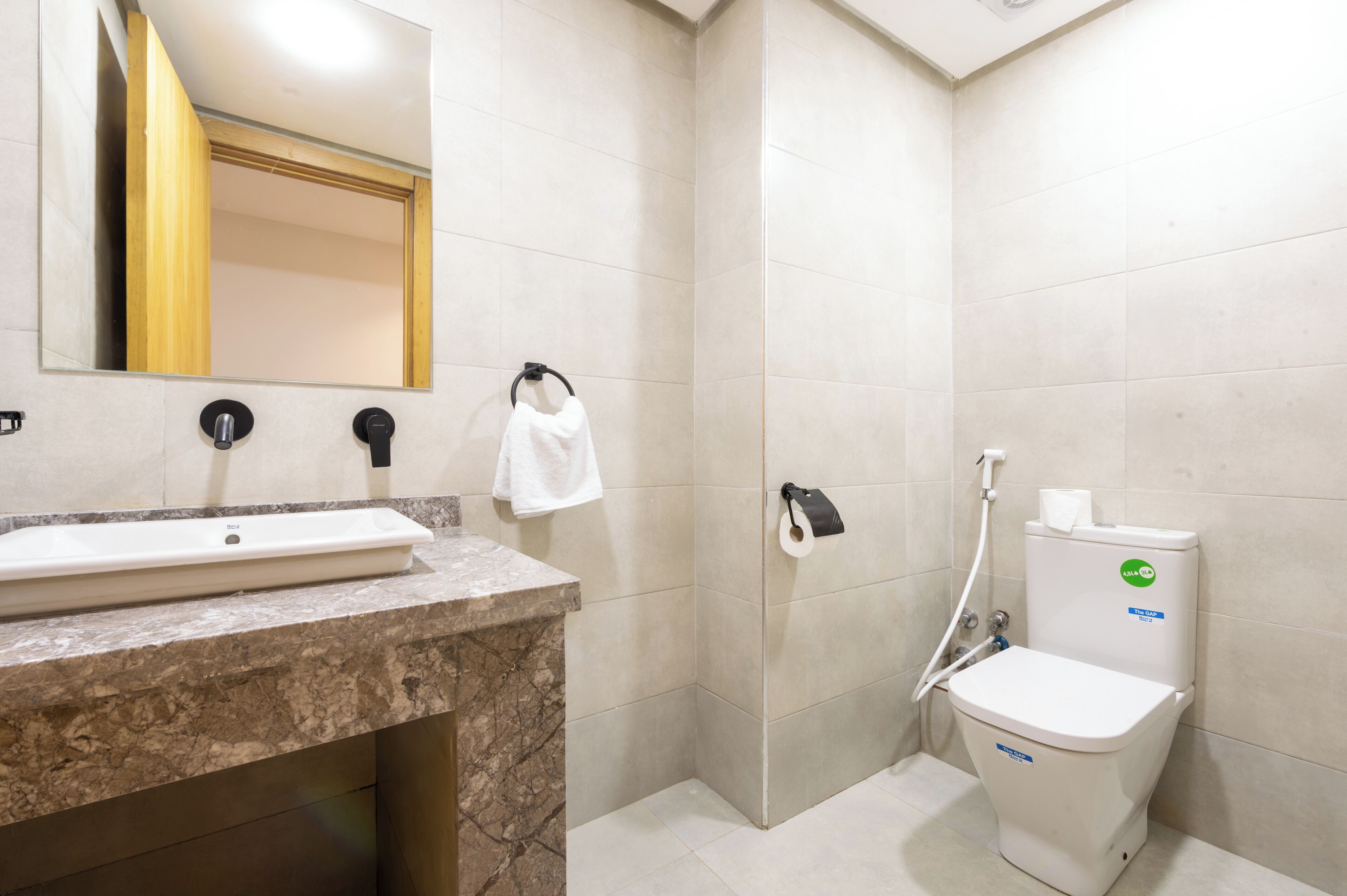 Ein Badezimmer mit Waschbecken, Spiegel, Handtuchhalter, Toilette und Dusche.
