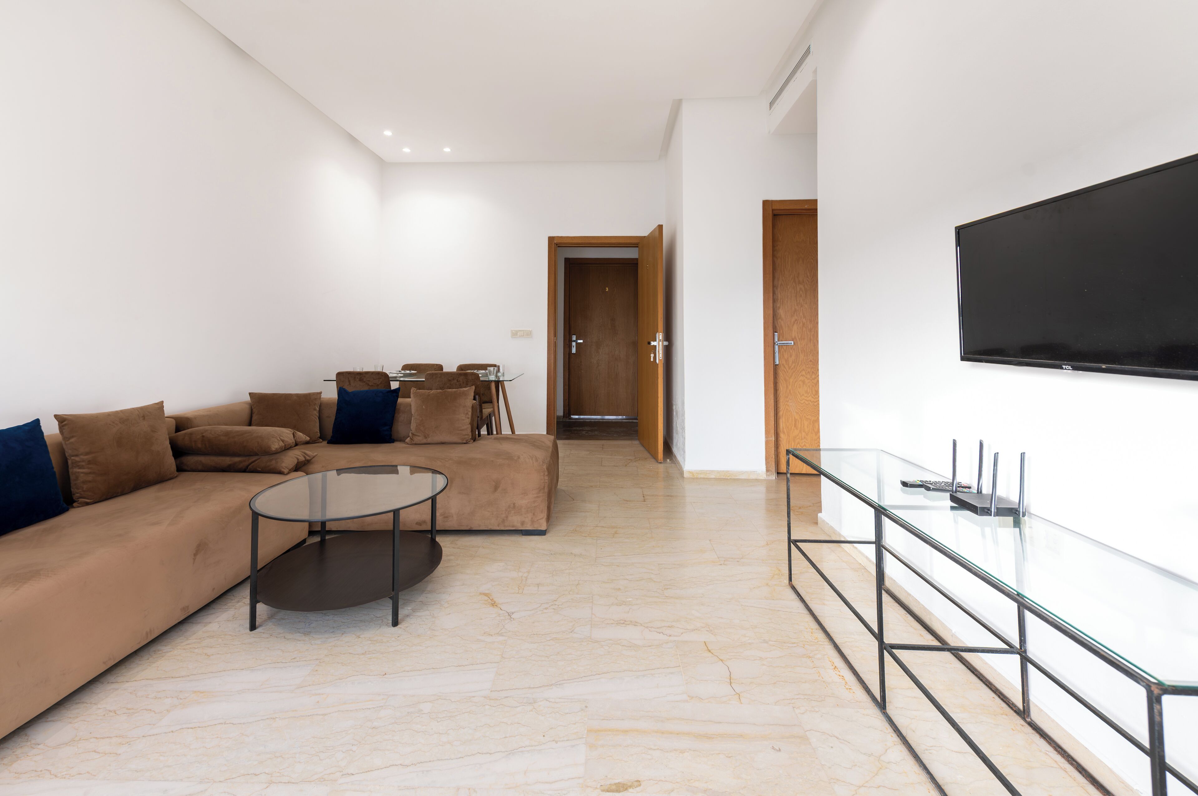 Una sala de estar moderna con sofá, mesa de centro y televisor montado en la pared.
