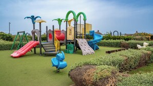 Een speeltuin met diverse speeltoestellen, waaronder glijbanen en schommels.