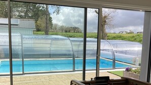 A room with a foosball table, large windows, and a view of a swimming pool.