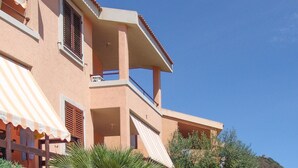 Ein mehrstöckiges Gebäude mit Balkonen, einem gestreiften Sonnenschirm und blauem Himmel.
