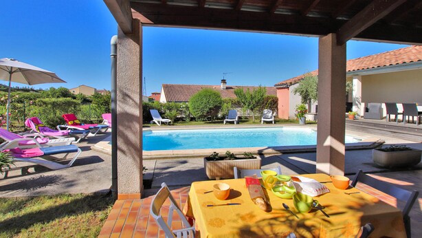 A covered outdoor area with a pool, lounge chairs, and a table with breakfast items. - Stunning home in Lussas (Lussas)