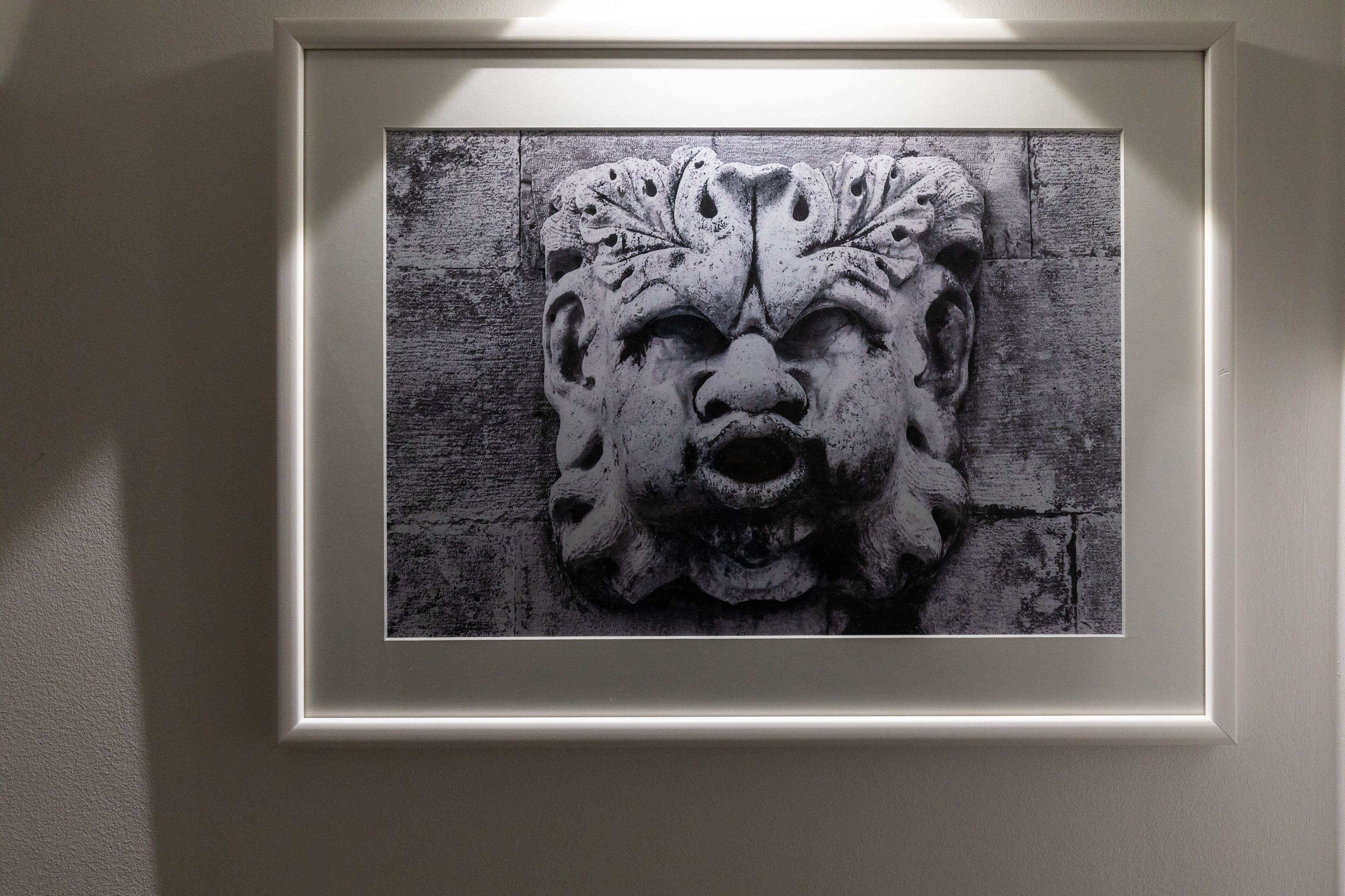 A framed artwork of a stone carving on a textured wall.