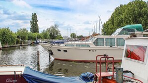 A marina with several boats docked, a covered area with a blue tarp, and a building with a sign reading "Doortje Amsterdam".