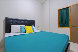 A bed with a tufted headboard, white and blue pillows, and a teal bedspread. - Athena Syariah Residence (Tangerang)