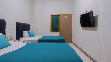 A hotel room with two beds, a television, and a door with a curtain.