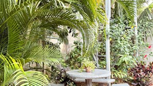 A garden patio with a stone table and benches, surrounded by lush greenery and a tiled floor. - 3 min walking distance to Nosara beach (Guanacaste)