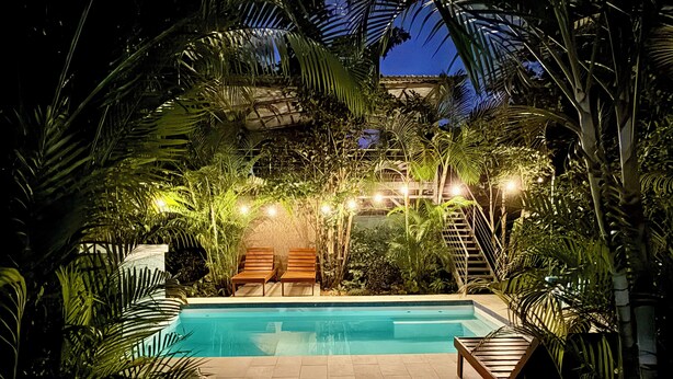 A pool area with two lounge chairs, surrounded by lush tropical plants and string lights. - 3 min walking distance to Nosara beach (Guanacaste)