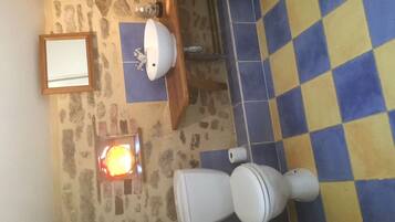 Une salle de bain avec un carrelage à motifs géométriques, des toilettes, un lavabo, un miroir et un luminaire fixé au mur.