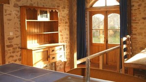 Una habitación rústica con mesa de ping pong, armarios de madera, un lavamanos y una ventana con cortinas.