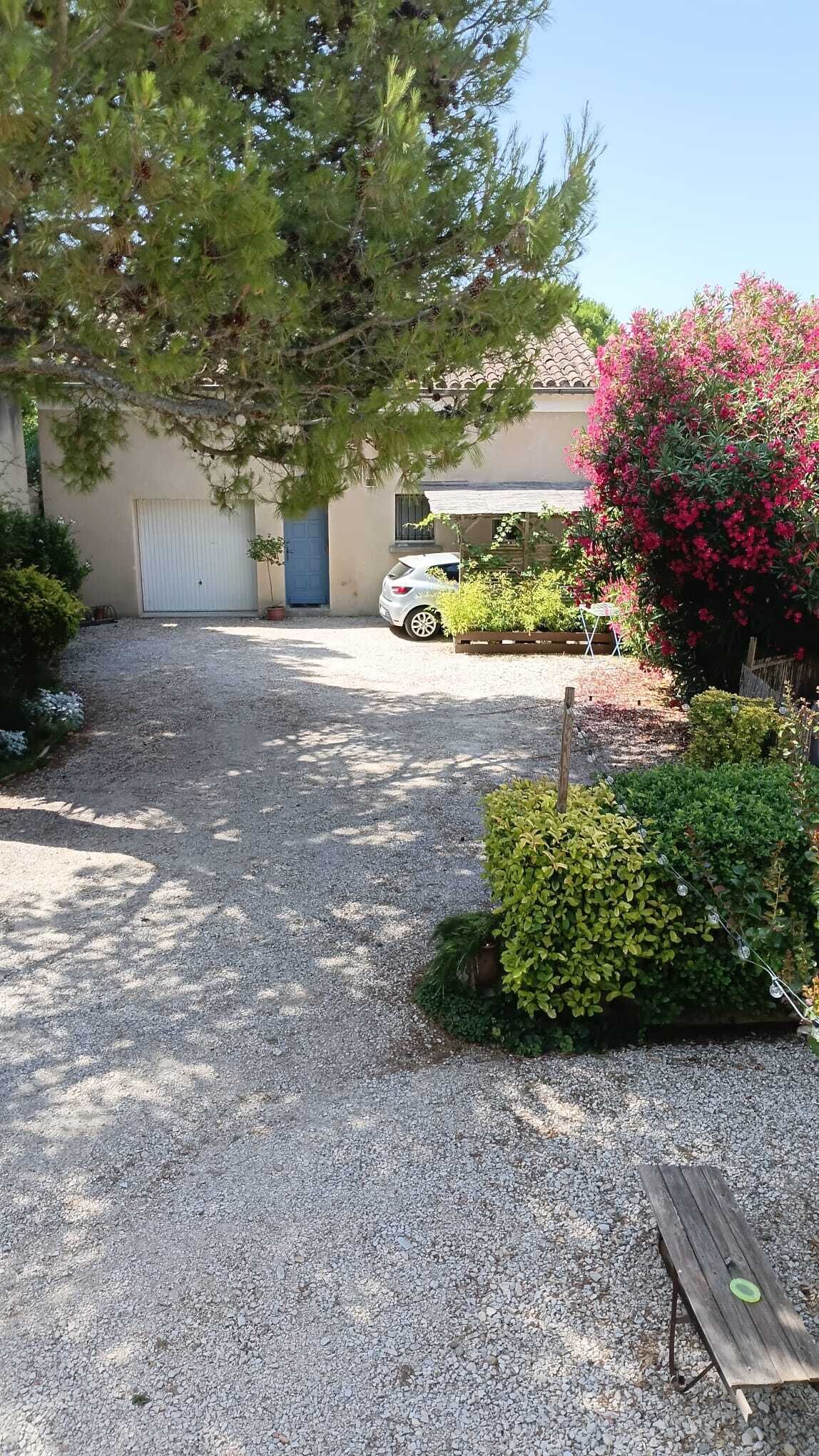 Une allée de gravier mène à une maison où une voiture est garée.