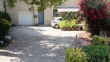 Une allée de gravier mène à une maison où une voiture est garée.