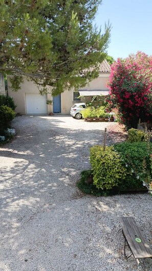 A gravel driveway leading to a house with a car parked in the driveway.