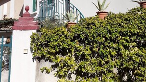 A building with a white facade, red-tiled roof, and green shutters. There is a staircase leading to a balcony with a metal railing. - PERNES LA PROVENCALE (Pernes-les-Fontaines)