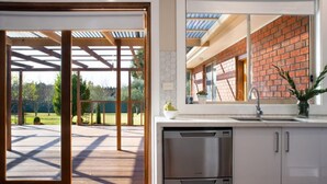 Cocina moderna con lavavajillas integrado, pared de ladrillo y un amplio ventanal con vistas a una terraza.