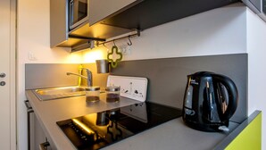 Une petite cuisine équipée d’une cuisinière, d’un évier et d’une machine à café.
