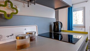 Une cuisine moderne dotée d’une plaque de cuisson à induction noire, d’une bouilloire et de deux bocaux en verre avec couvercles.