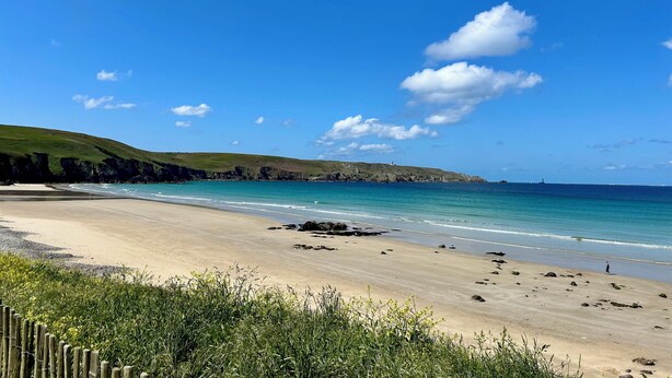 A beach with clear blue water, a sandy shore, and a grassy hill in the background. - Beachfront at Baie des Trépassés (Cléden-Cap-Sizun)