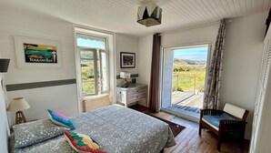 A bedroom with a bed, a dresser, a chair, and a view of the outdoors. - Beachfront at Baie des Trépassés (Cléden-Cap-Sizun)