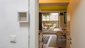 Un corridoio stretto che conduce a una sala da pranzo con tavolo e sedie, un quadro appeso al muro e una porta con l'interruttore della luce.