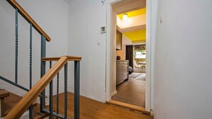 Una scala con corrimani in legno e un angolo cottura con soffitto giallo e vista all'esterno.