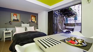 Camera d'albergo moderna con un letto, comodini, una scrivania e un vassoio per la colazione, oltre a vista sull'esterno.