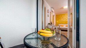 Une petite table ronde avec un plateau en verre, une assiette de fruits et deux verres.