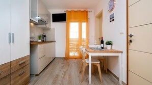 Une cuisine de taille réduite avec des meubles blancs, un plan de travail en bois et un coin repas comprenant une table et des chaises.
