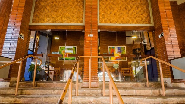 A staircase with metal railings leading to an upper level with a brick wall and a patterned ceiling. - Hotel Verdes Mares (Ouro Branco)
