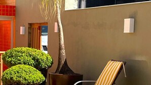 A patio area with striped lounge chairs and a large potted tree. - Hotel Verdes Mares (Ouro Branco)