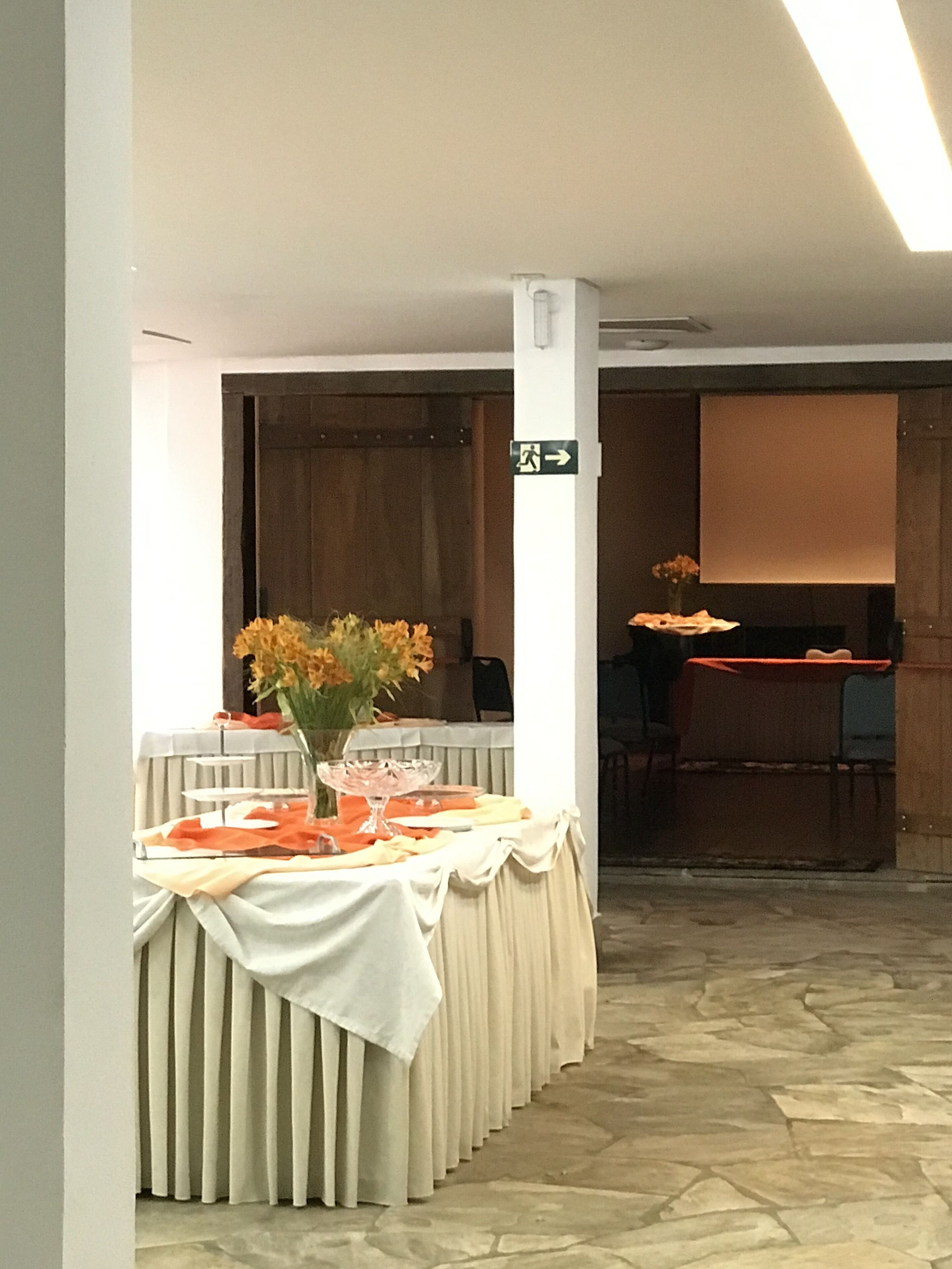 A conference room with a long table set for a meeting, a whiteboard, and a door with an exit sign.