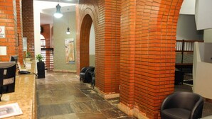 A reception area with a stone floor, brick walls, and a counter with a computer and a plant. - Hotel Verdes Mares (Ouro Branco)