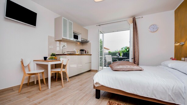A compact room with a bed, a small kitchenette, a dining area, and a balcony with a view. - TEREZA GOLD - Studio Apartment (Rovinj)