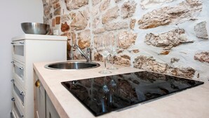 Een keuken met een stenen muur, een roestvrijstalen spoelbak en twee wijnglazen.