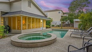 A residential backyard with a swimming pool, a covered patio area, and outdoor seating. - Beautiful East Beach Cottage with Pool (St. Simons)