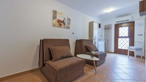 Een woonkamer met twee bruine banken, een kleine witte tafel en een schilderij aan de muur.