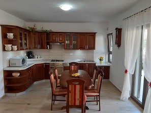 Une cuisine avec des meubles de rangement en bois, une table à manger avec des chaises, un four à micro-ondes, une cuisinière et un évier.