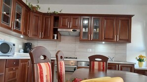 Een moderne keuken met houten kastjes, een rvs-fornuis en een eettafel met stoelen.