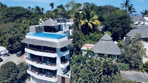 A multi-story building with a rooftop pool, surrounded by lush greenery and palm trees. - Casa Makawe - Adults Only (Sayulita)