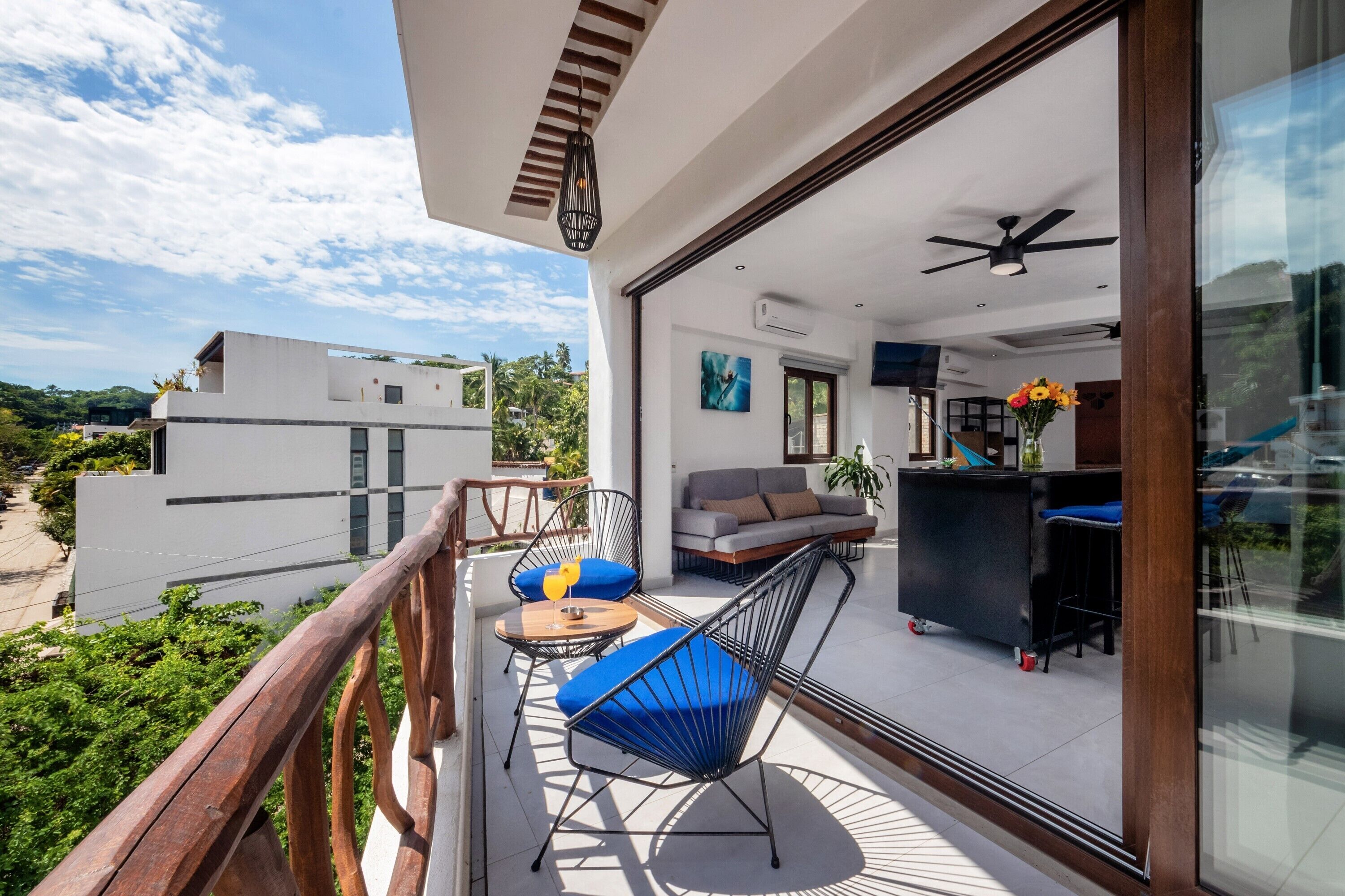 Un balcon avec une balustrade en bois, un canapé, une table basse et une chaise avec des coussins bleus.